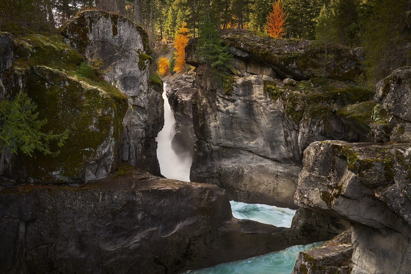 Nairn Falls on the Green River pouring through a rock gorge in Nairn Falls Provincial Park, with autumn colour on the cliffs