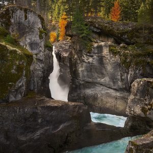 Nairn Falls on the Green River pouring through a rock gorge in Nairn Falls Provincial Park, with autumn colour on the cliffs