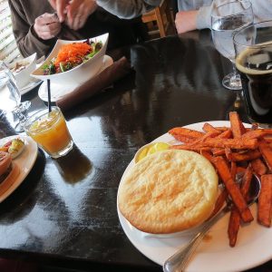 A pot pie with sweet potato fries and a dark beer on a table at Howe Sound Brewing in Squamish