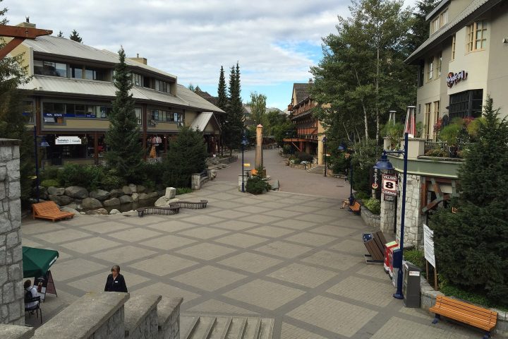 The Village Stroll in Whistler Village on a summer morning, with lodges and trees lining the pedestrian street