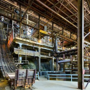 Inside the Britannia Mine concentrator: tiers of timber and steel machinery, ore-car tracks and railings under a high wooden roof