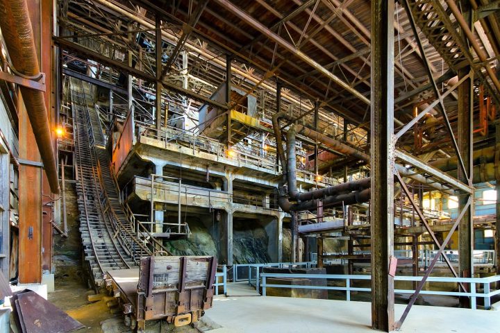 Inside the Britannia Mine concentrator: tiers of timber and steel machinery, ore-car tracks and railings under a high wooden roof
